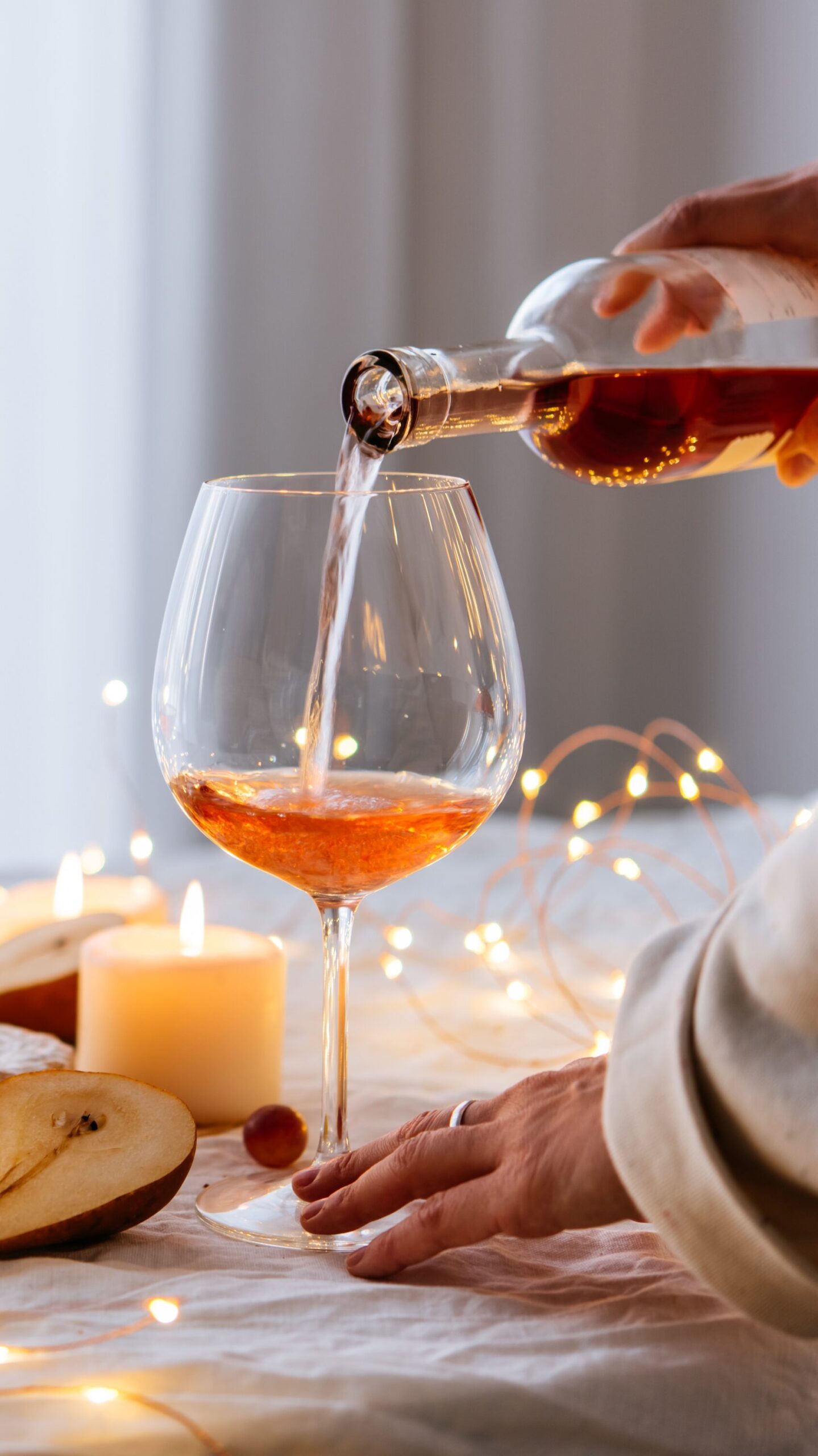 pouring rose wine with fairly lights background 